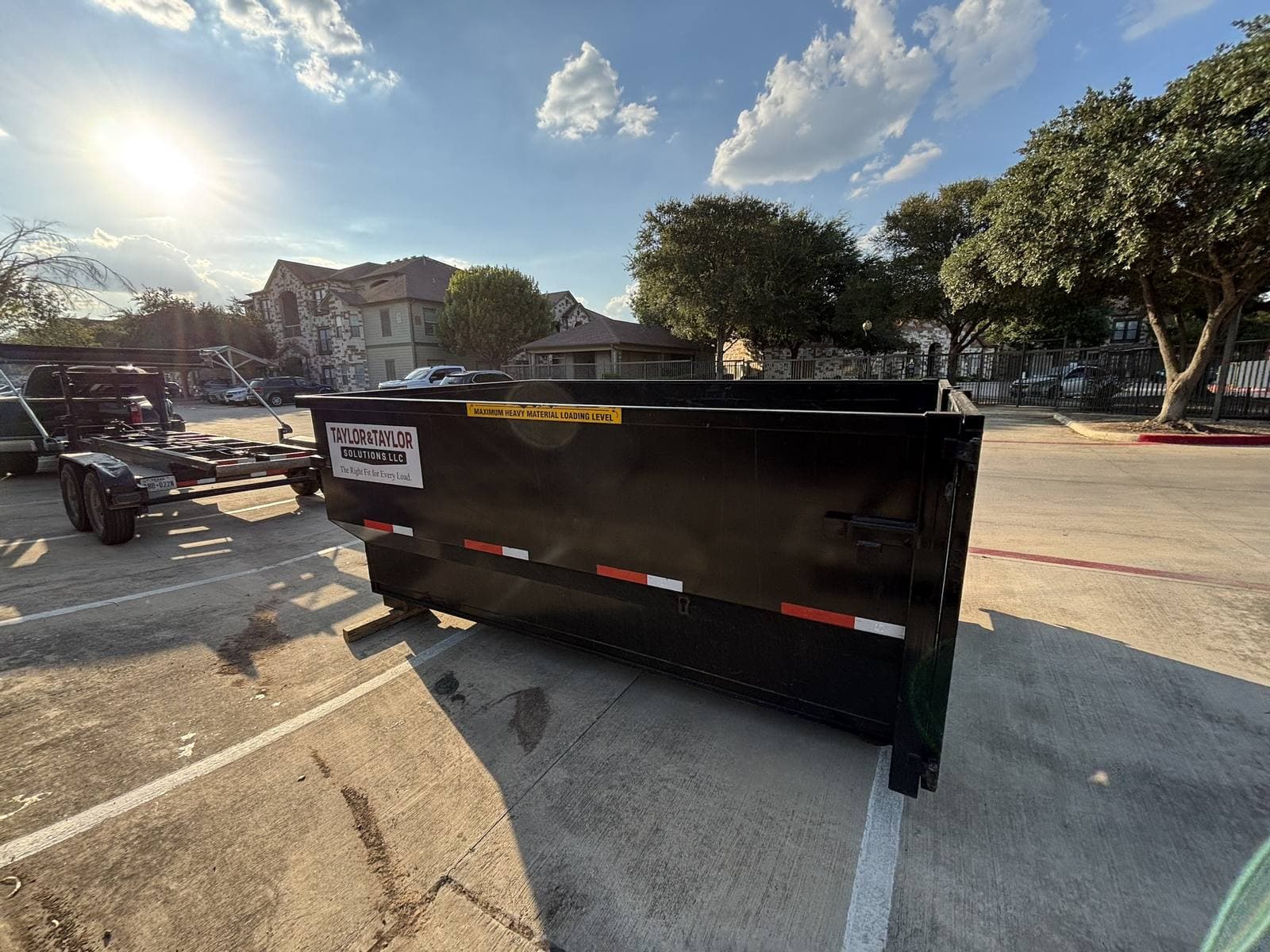 Taylor & Taylor dumpster placed in an apartment community parking lot
