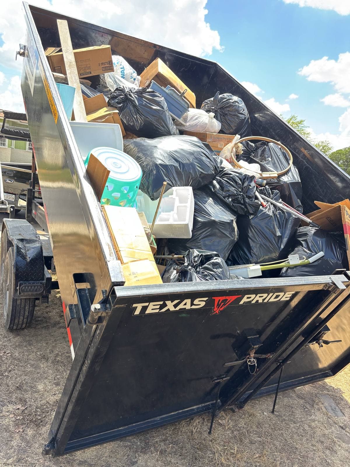 Taylor & Taylor dumpster tipped up, full of bags and boxes from a household cleanout