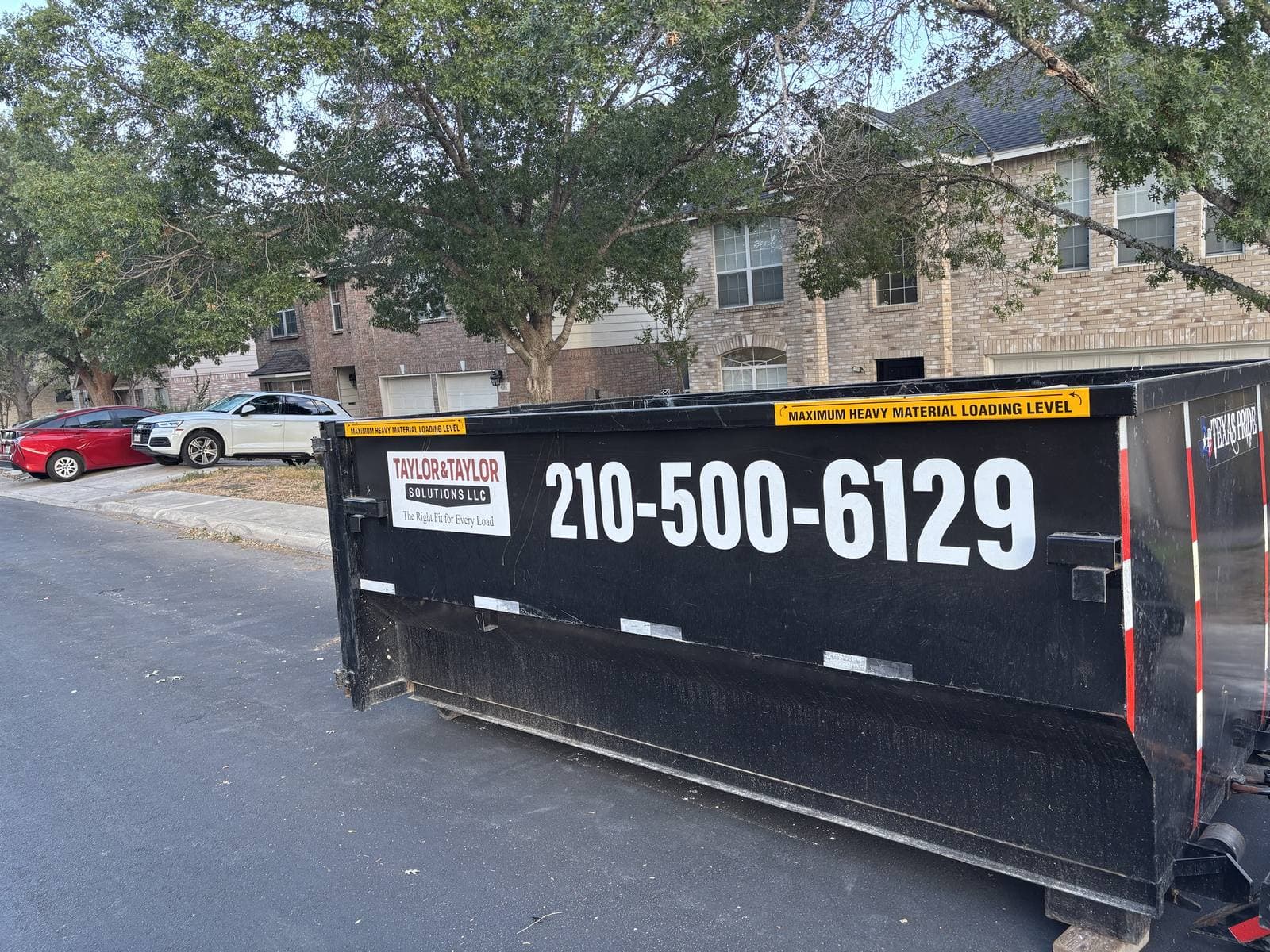 Taylor & Taylor dumpster at the curb in front of two-storey brick homes