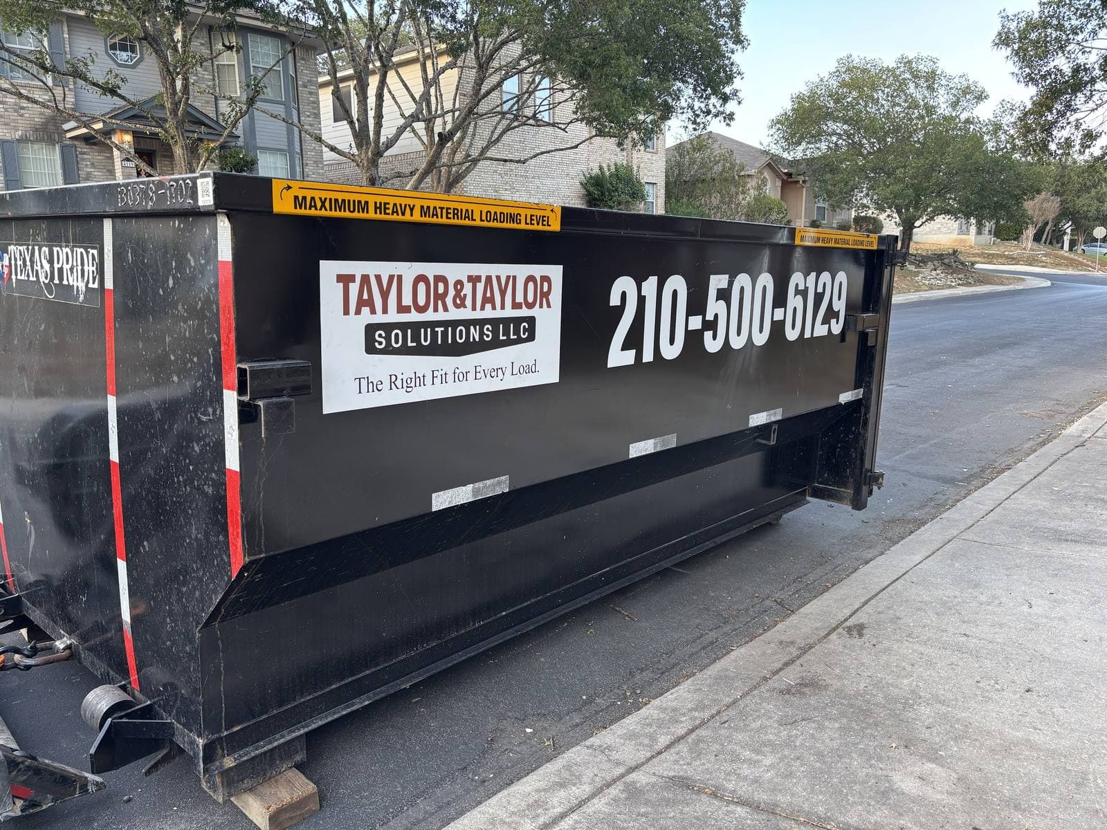 Taylor & Taylor dumpster at the curb on a residential street, logo and phone number on the side