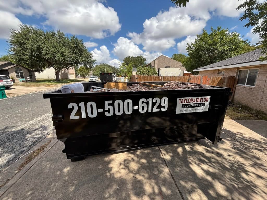 Taylor & Taylor dumpster on a driveway partially loaded with demolition debris