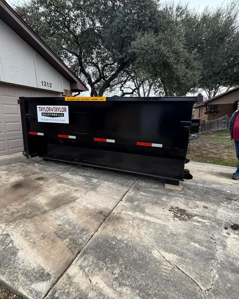 Taylor & Taylor dumpster placed on a residential driveway in front of a suburban home