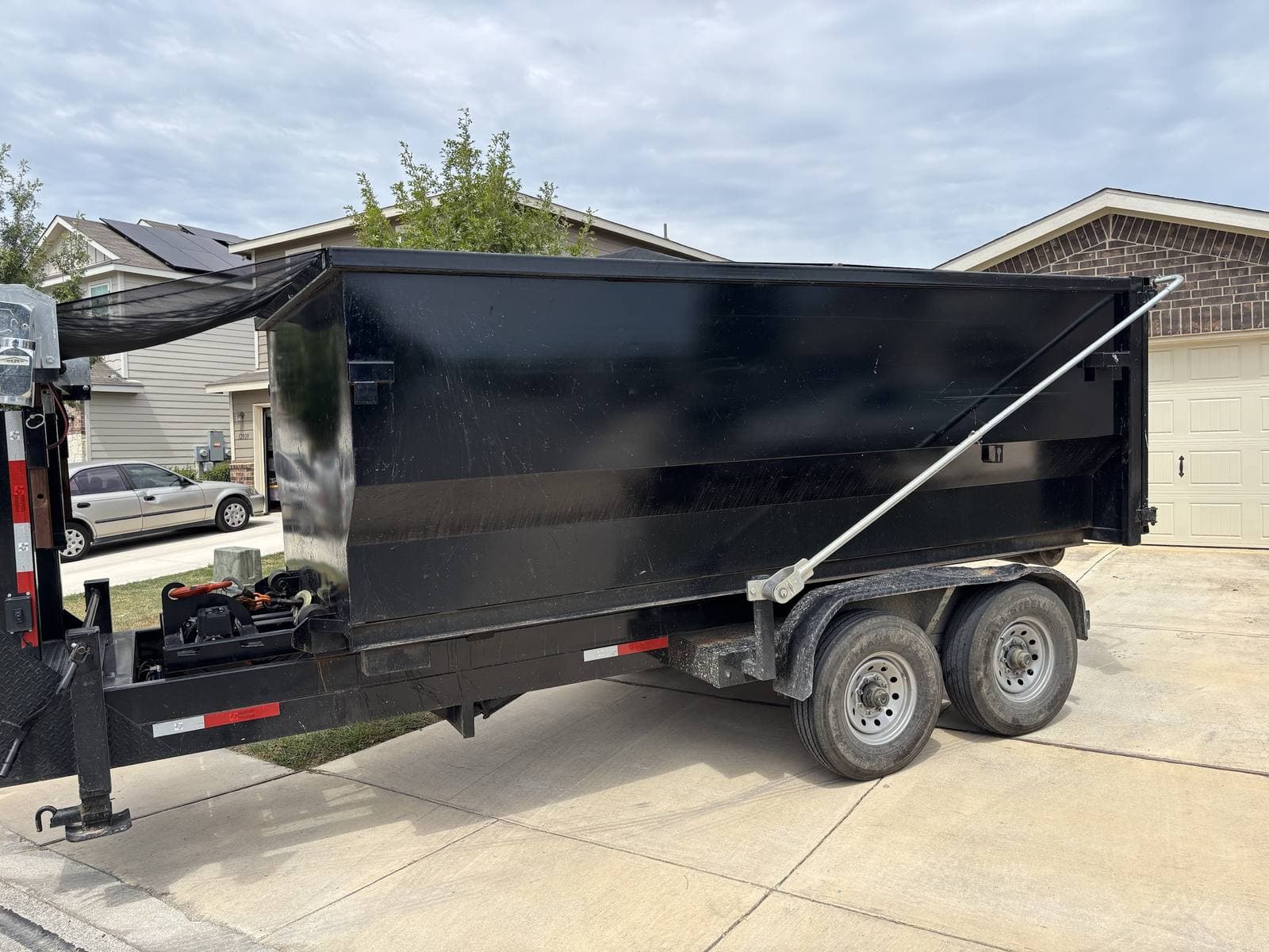 Taylor & Taylor roll-off dumpster on its trailer, backed into a residential driveway