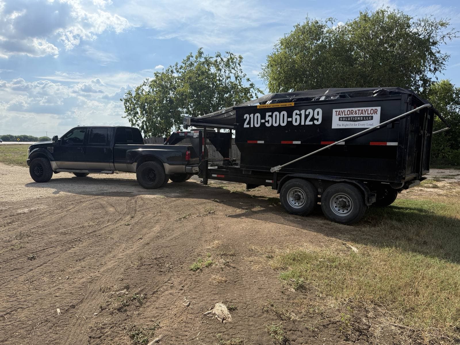 James's black dually towing a loaded, tarped Taylor & Taylor dumpster on its trailer